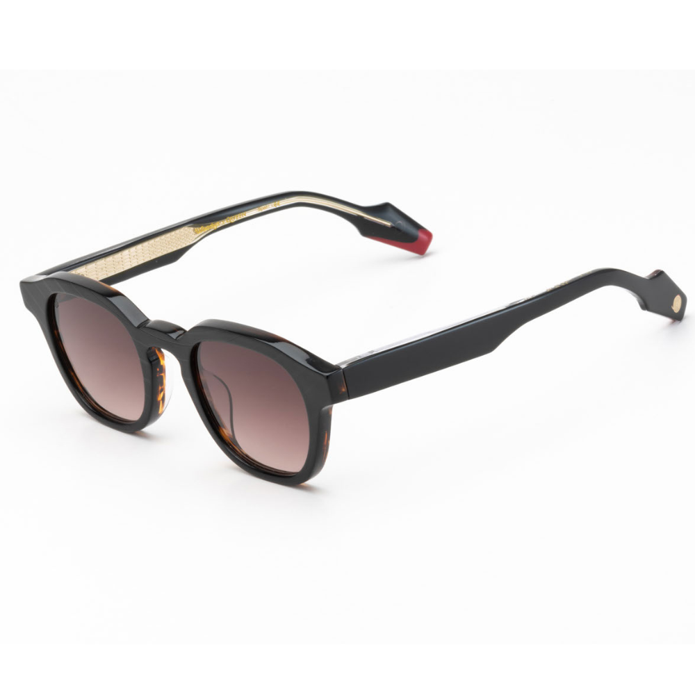 Woodys x Queen Dust C1 sunglasses – three-quarter view showing guitar-engraved metal core and laminated end-pieces

