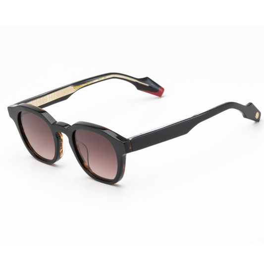 Woodys x Queen Dust C1 sunglasses – three-quarter view showing guitar-engraved metal core and laminated end-pieces
