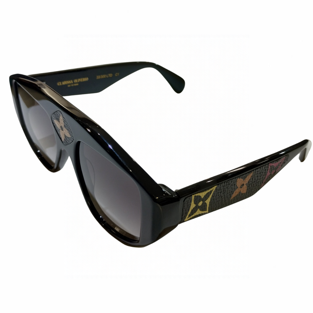 Clarissa Oliverio Michelangelo Mash-Up sunglasses, three-quarter view showing the black acetate frame, grey gradient lenses and floral monogram leather detailing.
